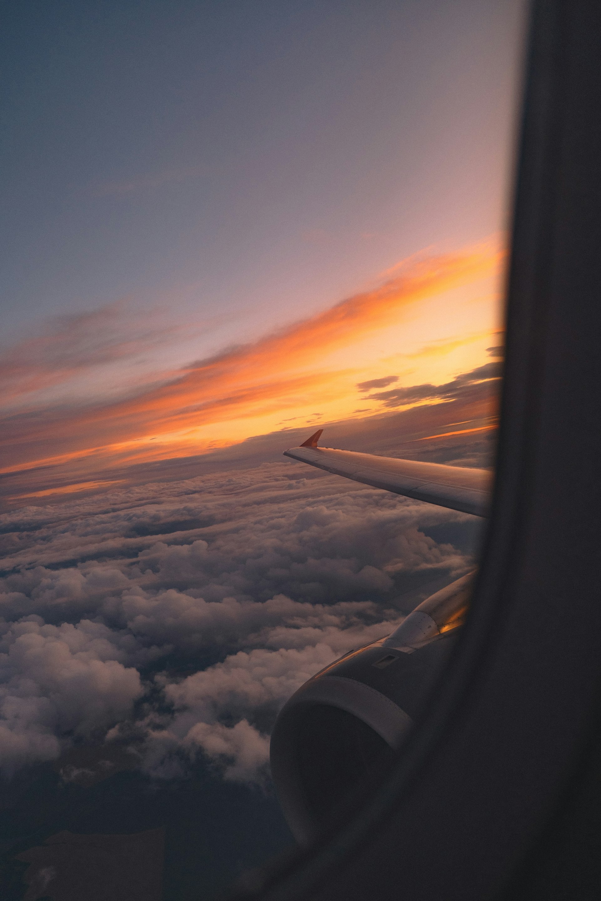 Airplane wing over golden clouds at sunset